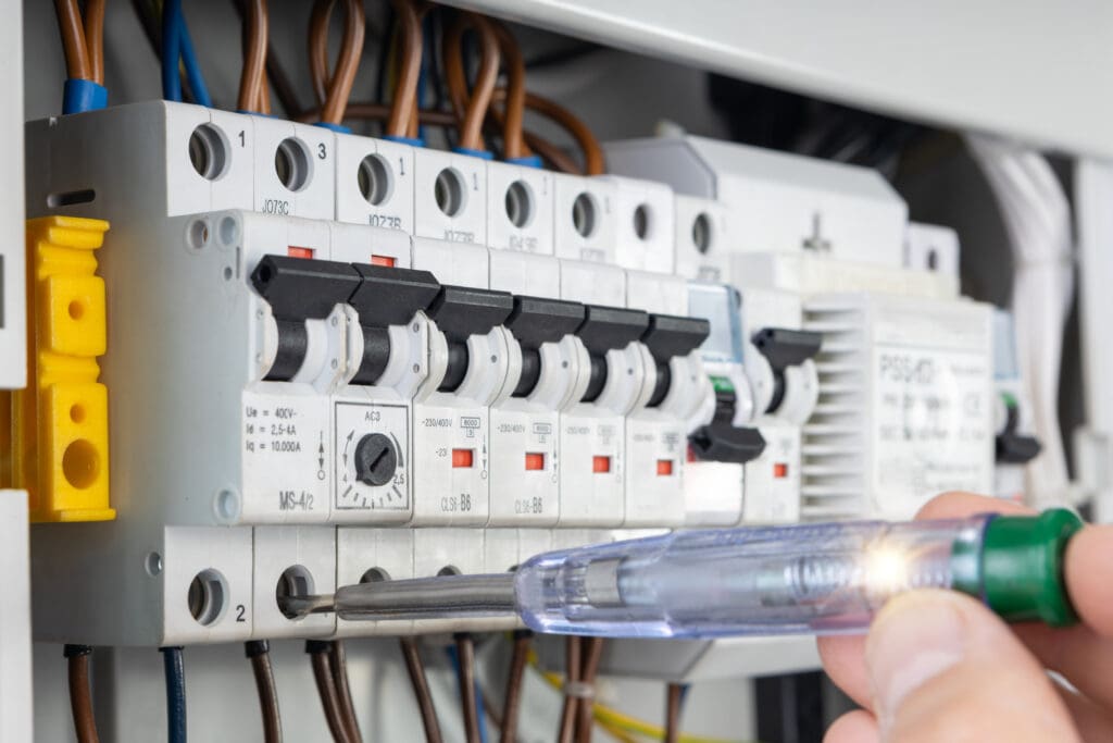 Close up of an electrician using a voltage tester on circuit breakers in an electrical panel