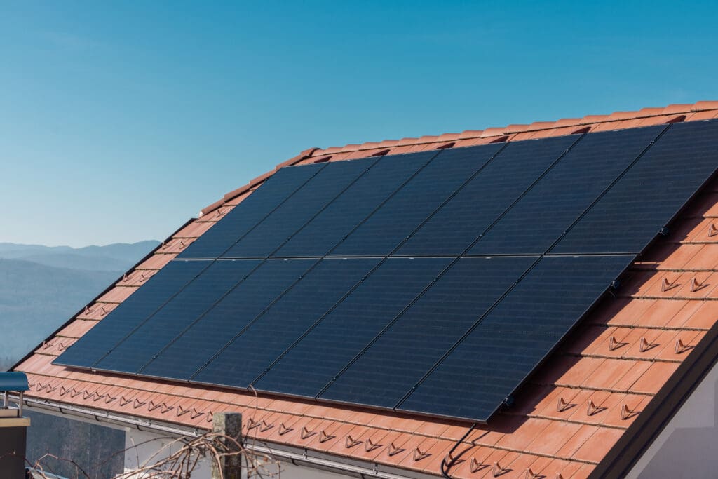 Multiple solar panels for electricity installed on a red tile wall of domestic house. Modern solar energy, eco friendly energy generation, sunny day..