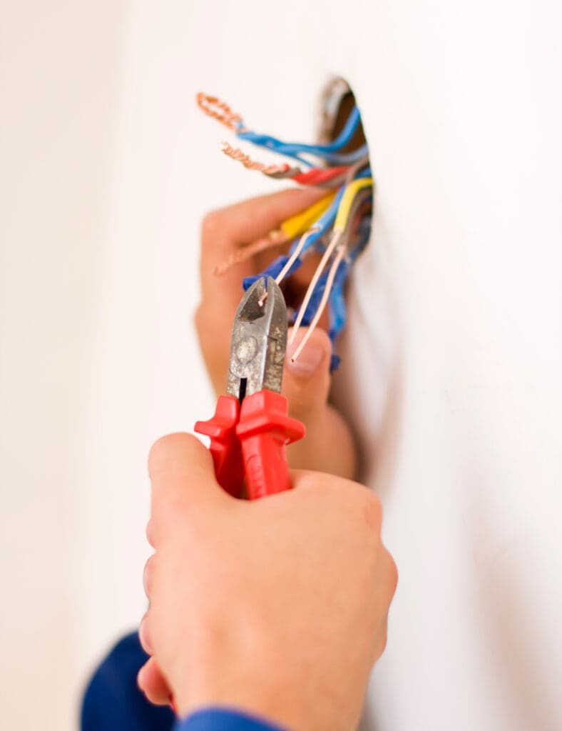 An electrician binding copper wires together and sealing them with insulation stripe.